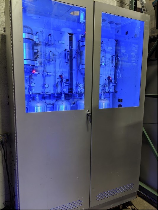 Large industrial cabinet with stainless steel tanks and pipes with ultraviolet lighting